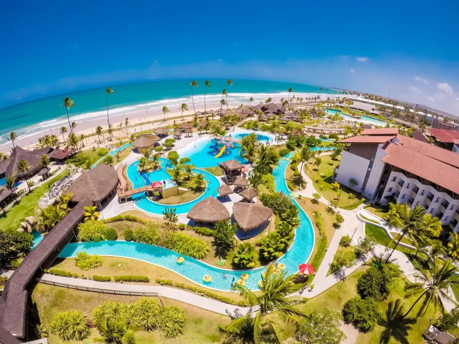 Vista aérea panorâmica de drone do complexo de lazer e parque aquático do Enotel Porto de Galinhas, exibindo o circuito do rio lento, piscinas infantis, blocos de apartamentos e a praia ao fundo